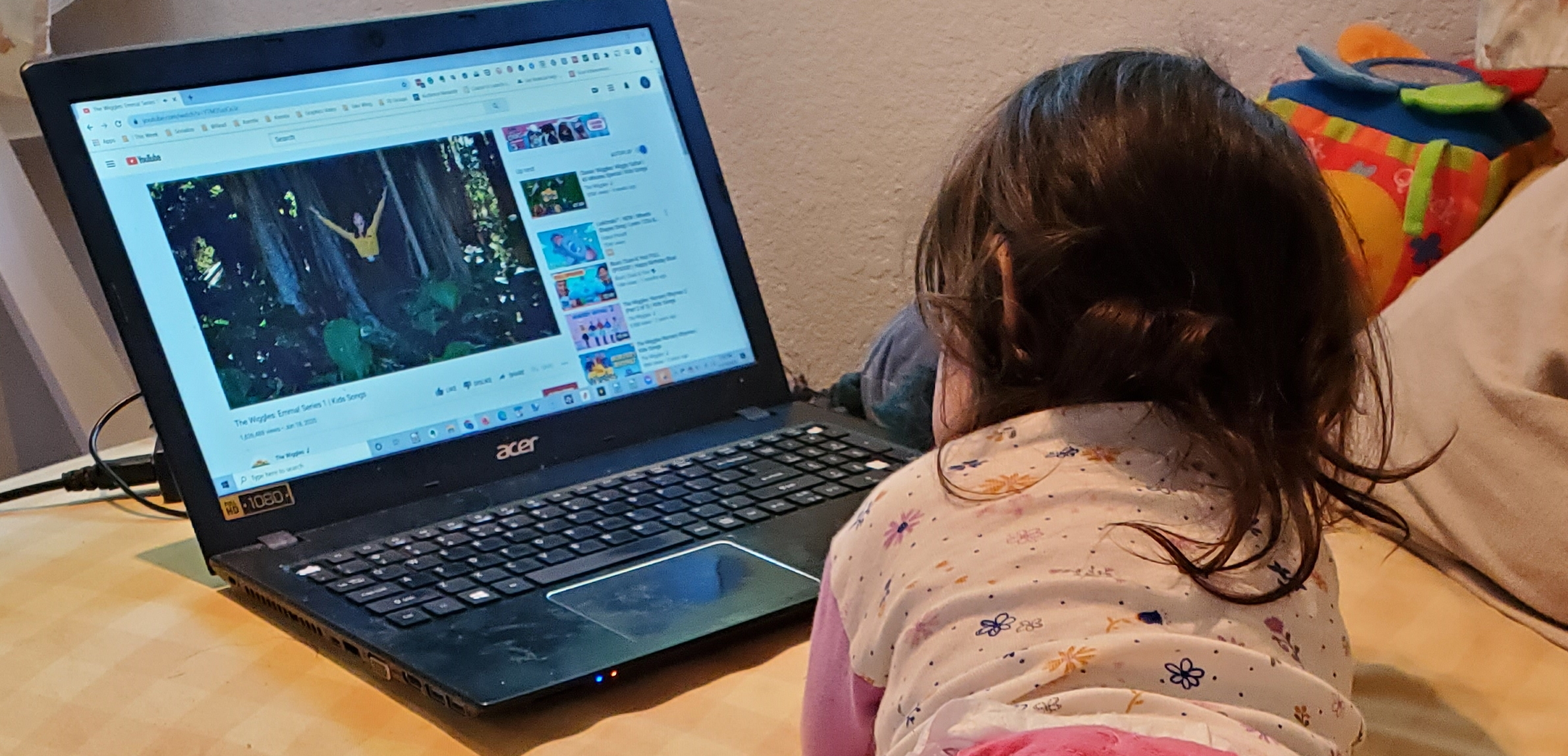 baby watching laptop with Wiggles on YouTube on yellow couch
